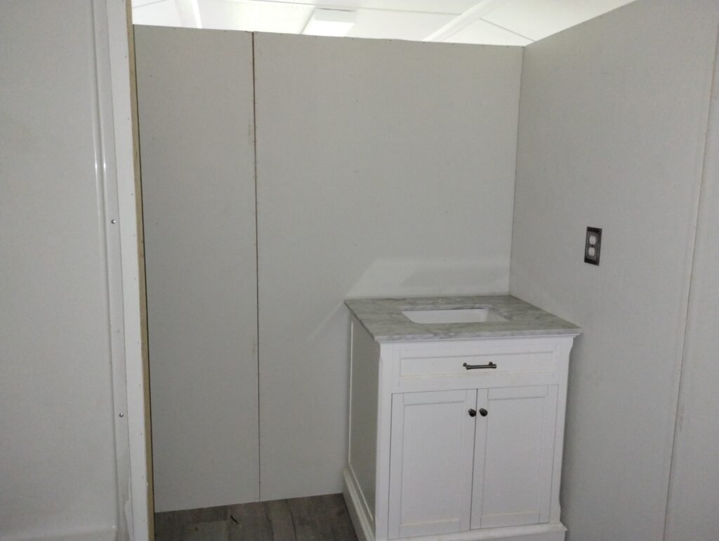 view from the bathroom door, there is a sink to the right against the back wall and a bathtub shower combo to the left