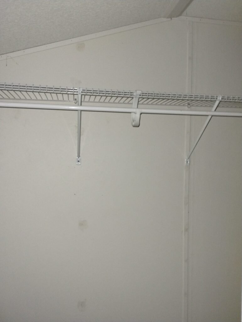 looking directly into the closet from the door , there is an empty wire shelf with a rod for hanging clothes