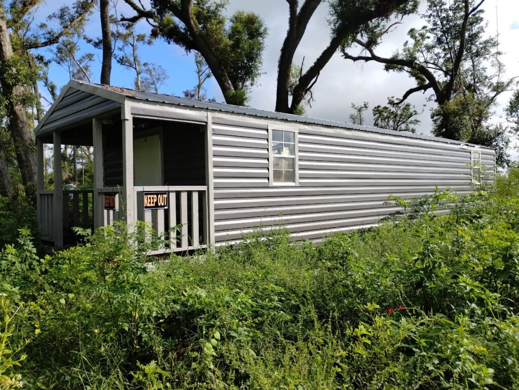 grey tiny home with porch surrounded by trees
