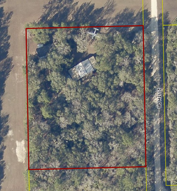 aerial view of 3.5 acre property with house and airplane hanger with many trees